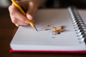 person holding pencil writing on notebook — Foto por Thought Catalog na Unsplash